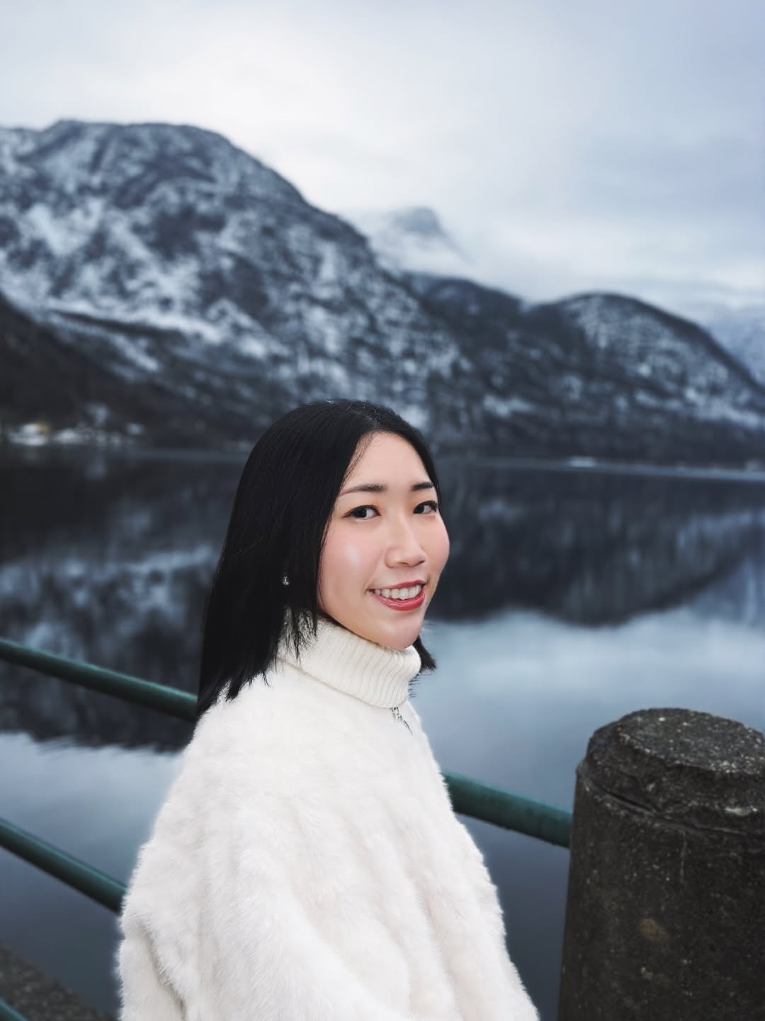 Shanna smiling in front of a snowy mountain lake in Hallstatt