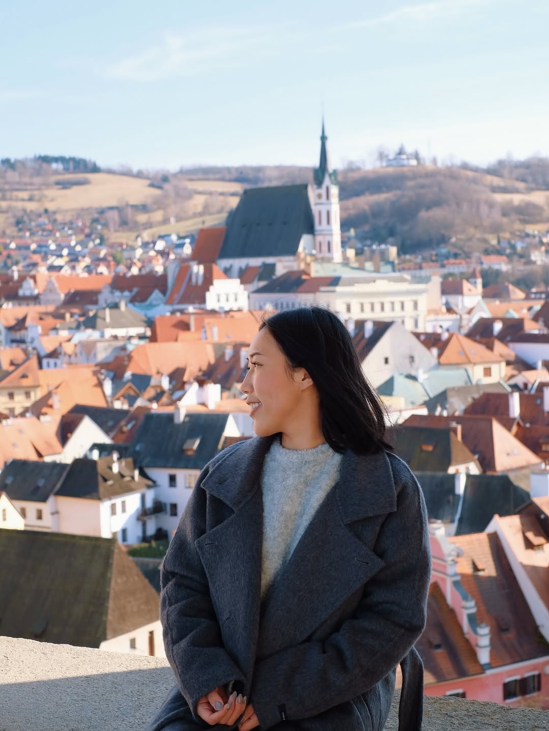 Shanna looking out over red rooftops and a church tower in Český Krumlov