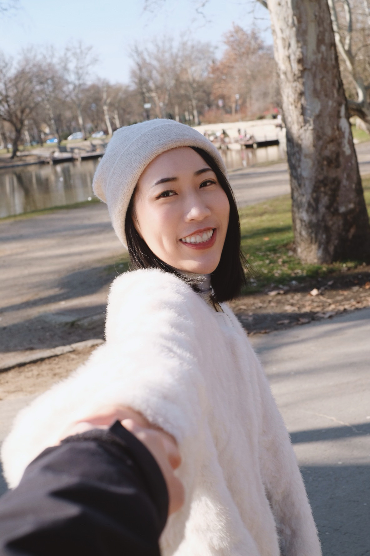 Shanna smiling, reaching back to hold Martin’s hand on a winter walk